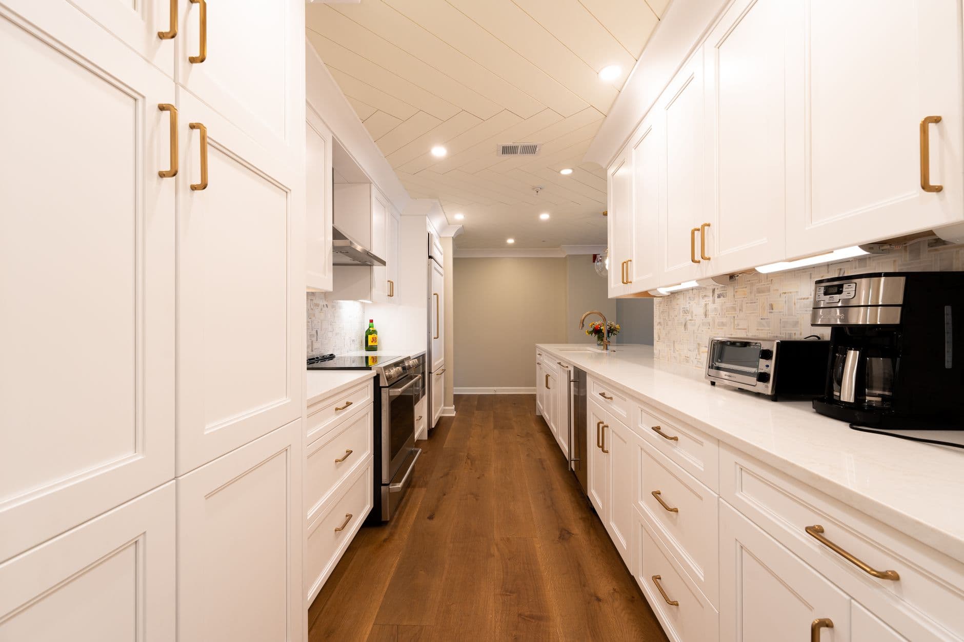 Bright modern kitchen with white cabinets and wood flooring.