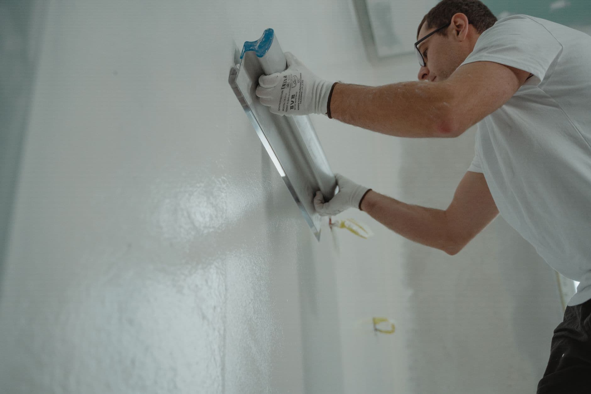 Contractor applying plaster during interior renovation finishing work.